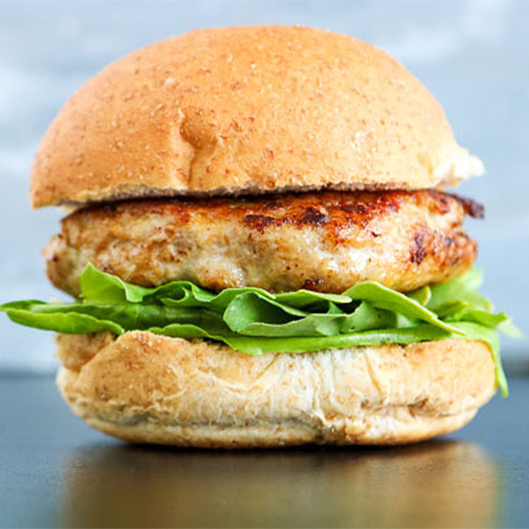 A turkey burger on a bun with lettuce on it.