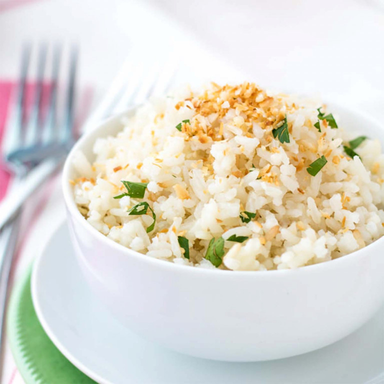 Coconut jasmine rice in a bowl with coconut and cilantro on top.