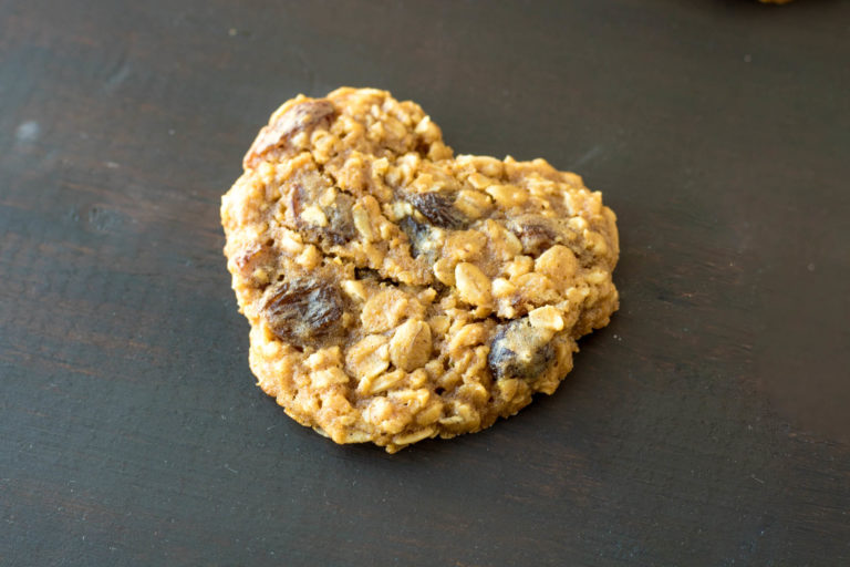 Heart shaped Oatmeal Raisin Cookies on a dark counter.