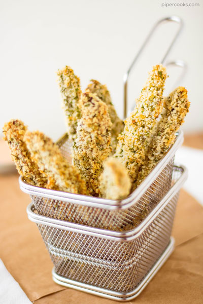 Breaded portobello fries standing up in a metal fry basket.