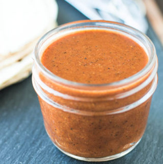 Red Enchilada sauce in a jar on a black background | Pipercooks