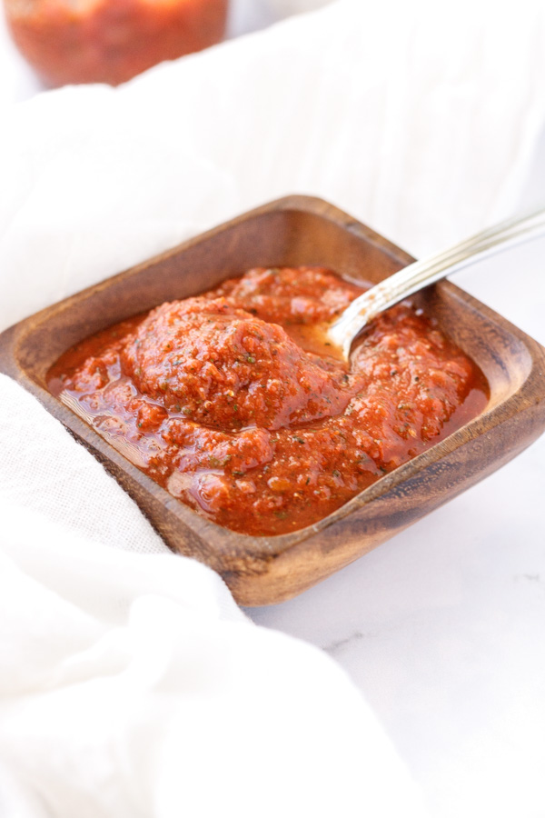 Pizza sauce in a square wooden bowl.