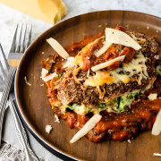 A chicken breast stuffed with cheese and spinach on tomato sauce with a crusted exterior and tomato and cheese on top.