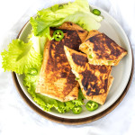 Grilled burritos on a plate, topped with jalapeno slices.