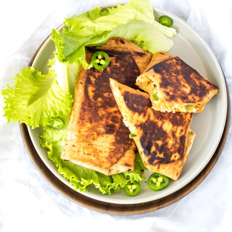 Grilled burritos on a plate, topped with jalapeno slices.