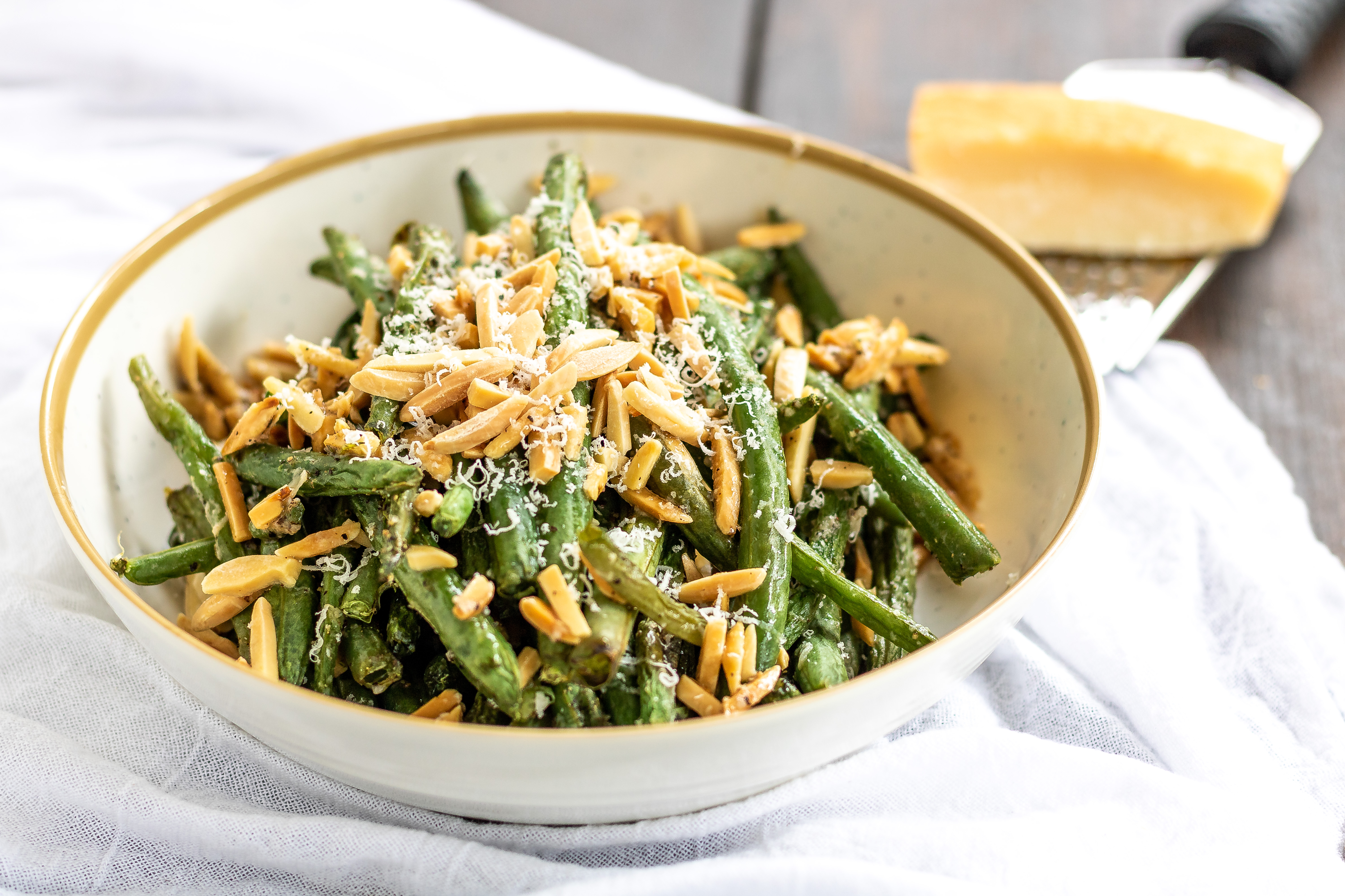 green beans in a bowl with almonds and parmesan cheese