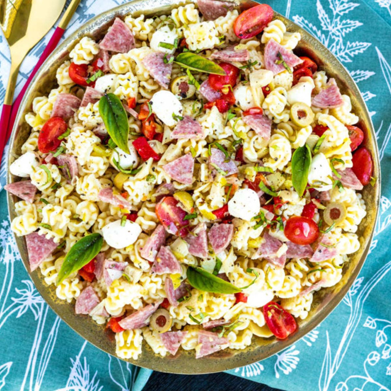 Pasta salad with meat, tomatoes and cheese in a bowl.