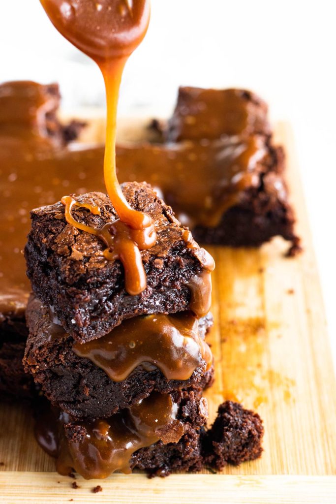 stack of three fudgy brownies with salted caramel sauce on top