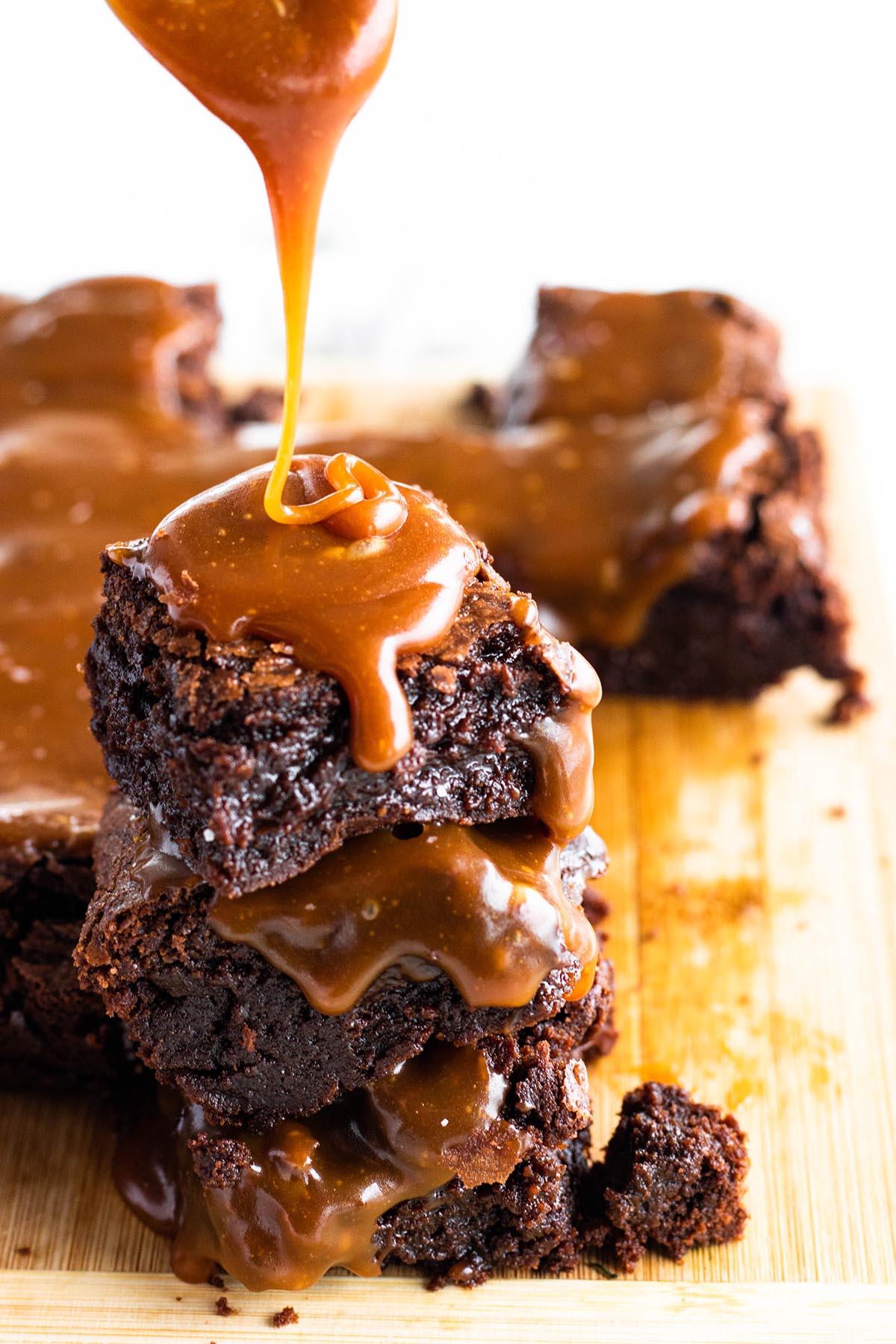 stack of three fudgy brownies with salted caramel sauce on top