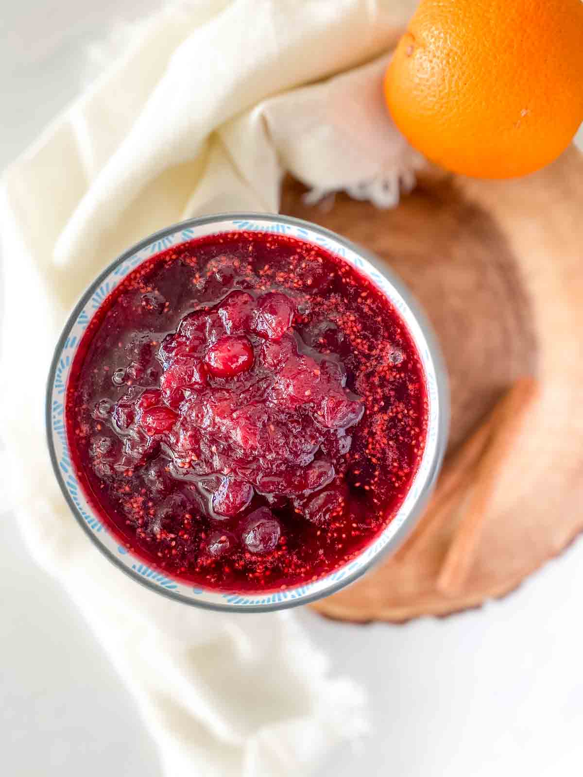 homemade cranberry sauce with an orange and cinnamon stick beside it