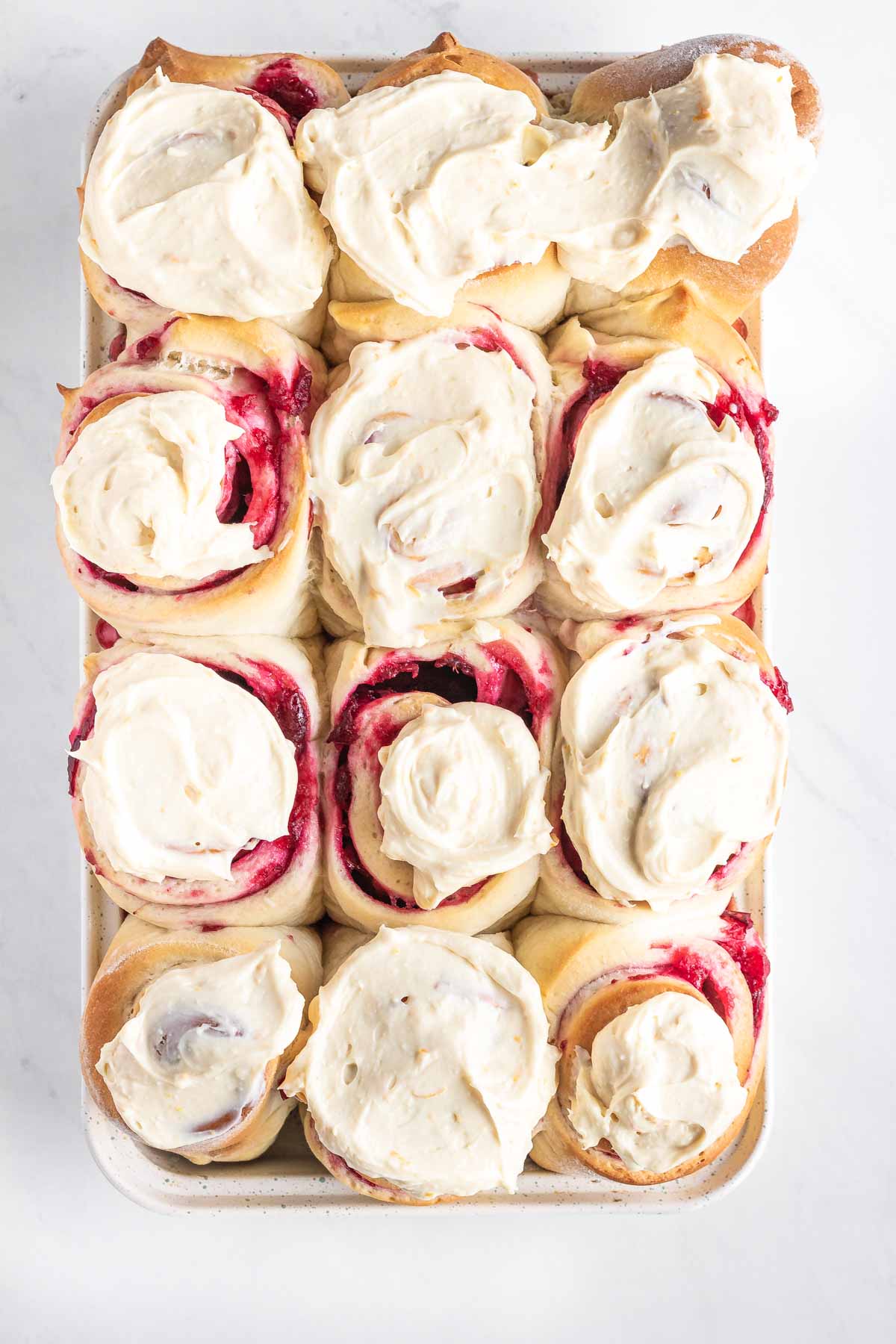 12 iced cranberry sweet rolls in a pan