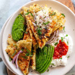 A sliced potato rosti on a plate with sour cream, sambal oelek, avocado, onion, and cheese on top.
