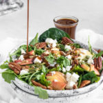 pouring balsamic dressing on a spinach salad