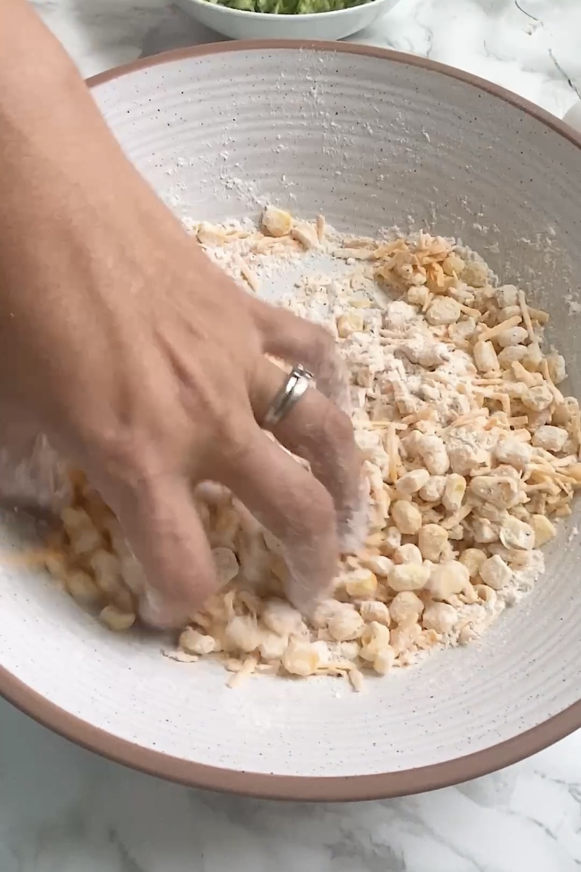 Corn is mixed into a flour by hand in a large mixing bowl.
