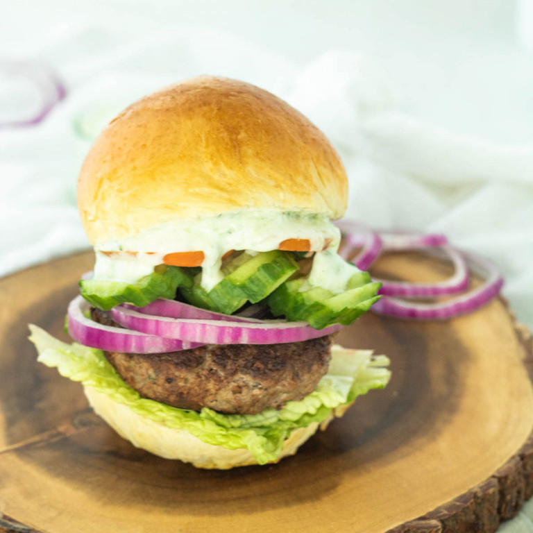 Greek turkey burger on a wood platter