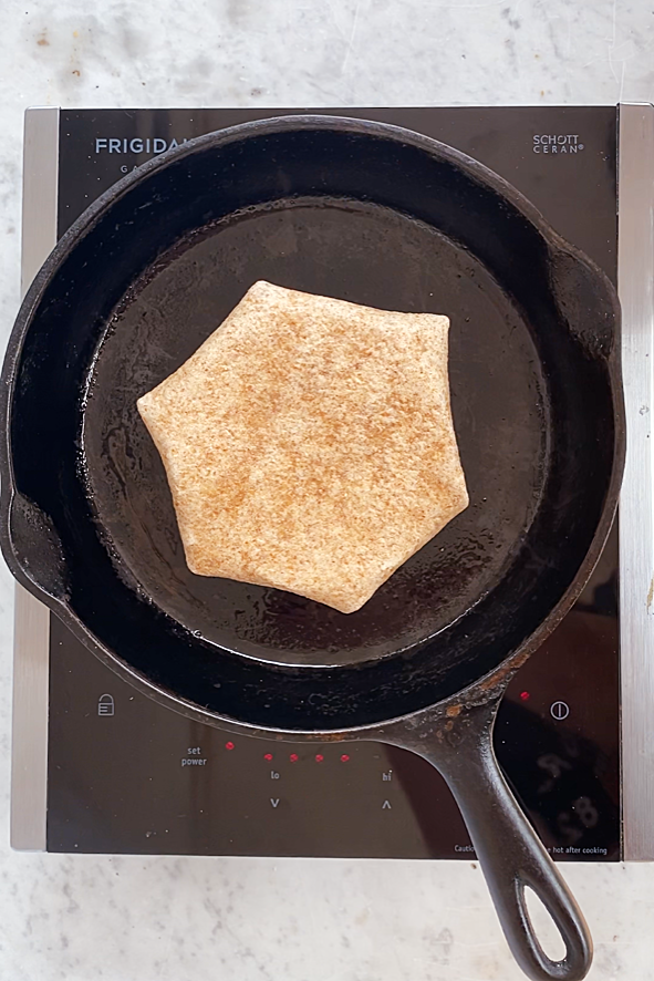 frying a breakfast crunchwrap in a cast iron pan