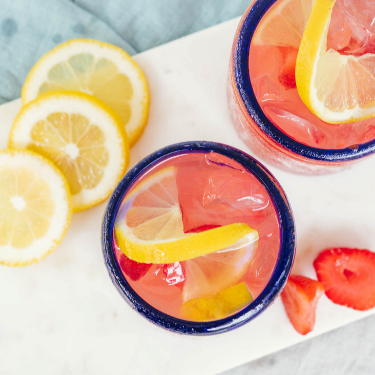 two pink cocktails in blue rimmed glasses