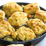 Pot pie topped with biscuits in a cast iron skillet.