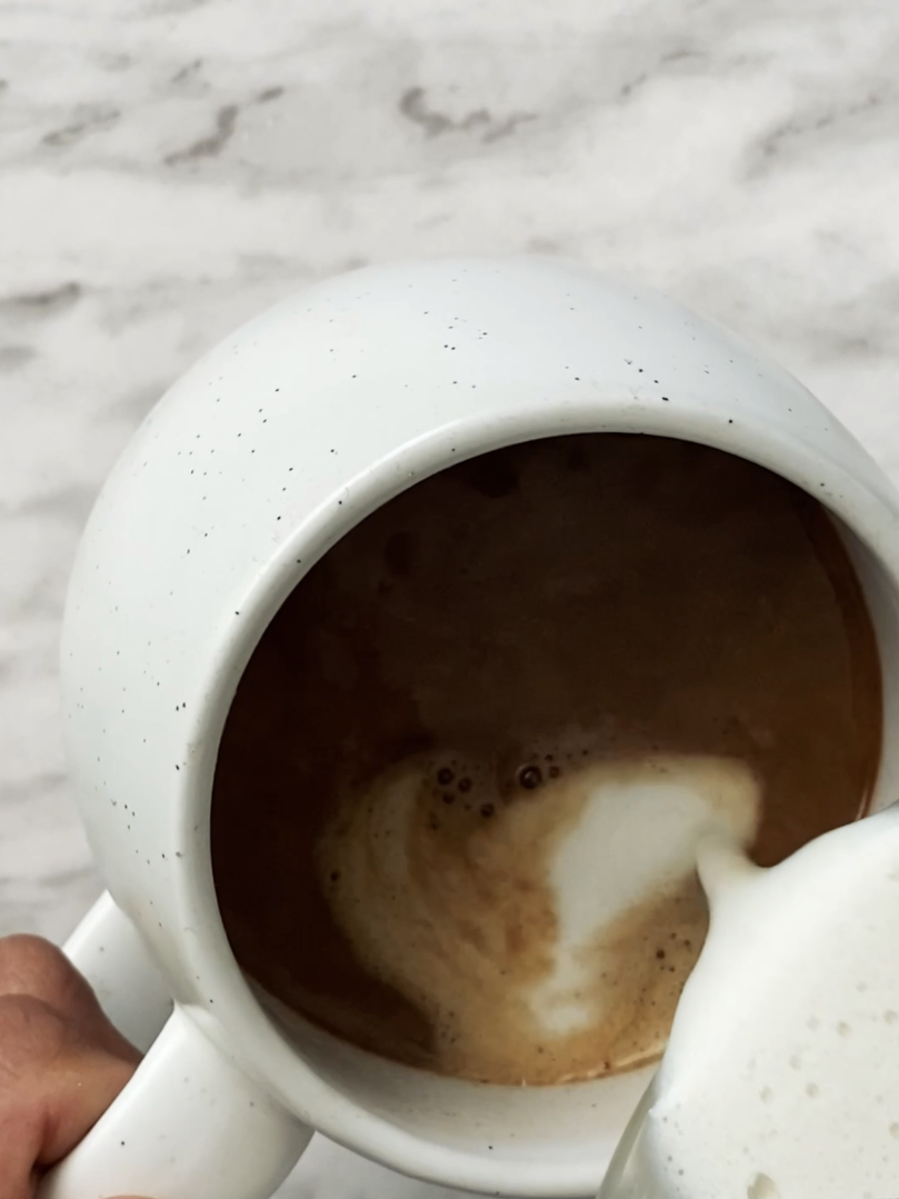 pouring frothed milk into coffee