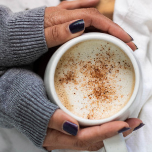 hands holding a prepared gingerbread latte in a white mug