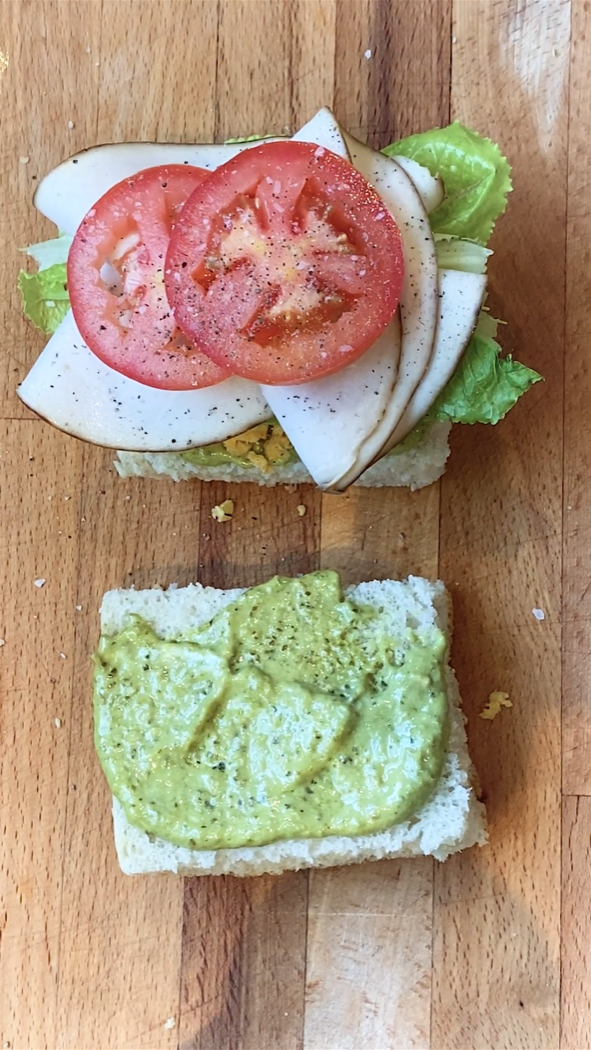 an open sandwich with tomatoes on one side and pesto mayo the other side.