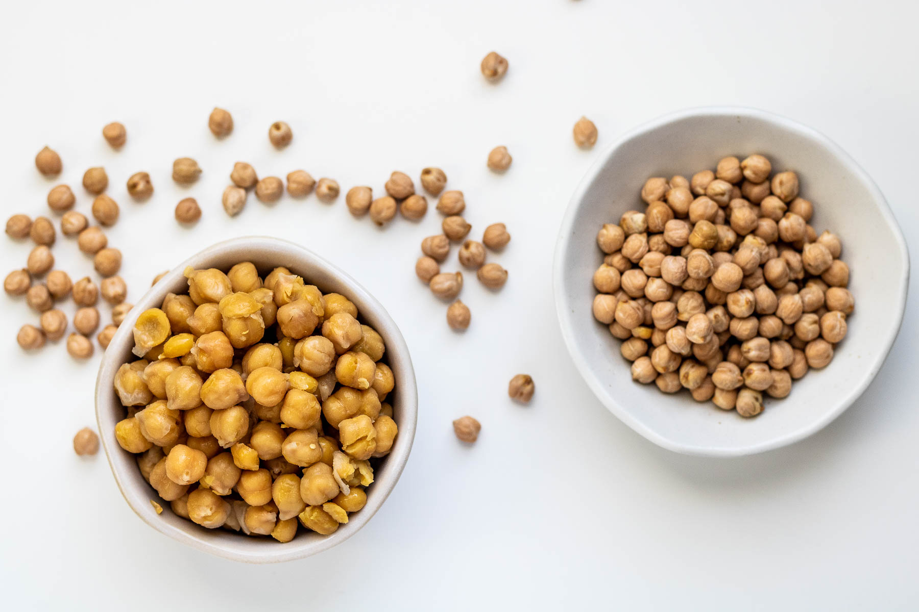 a bowl of cooked chickpeas on the left and a bowl of dried chickpeas on the right.