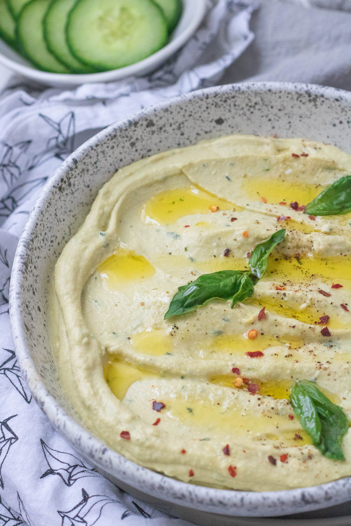 hummus garnished with basil and olive oil in a bowl.