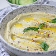 hummus garnished with basil and olive oil in a bowl.