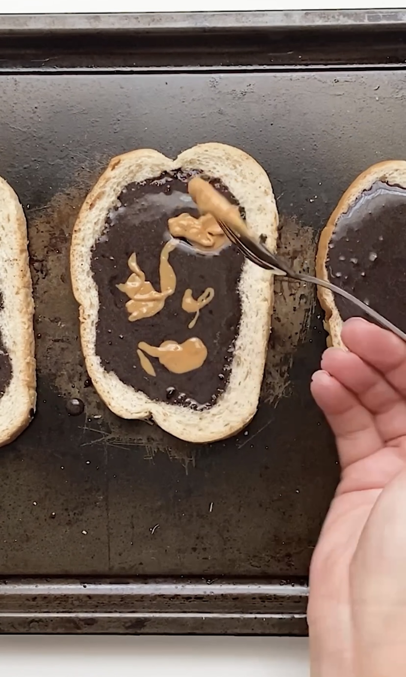 adding peanut butter to chocolate covered toast.