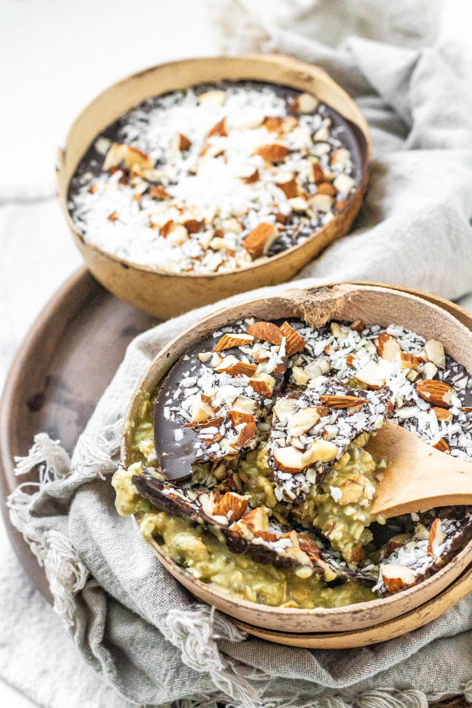 Overnight oats in a coconut bowl with a chocolate, almond, and coconut topping.