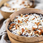 Overnight oats in a coconut bowl with a chocolate, almond, and coconut topping.