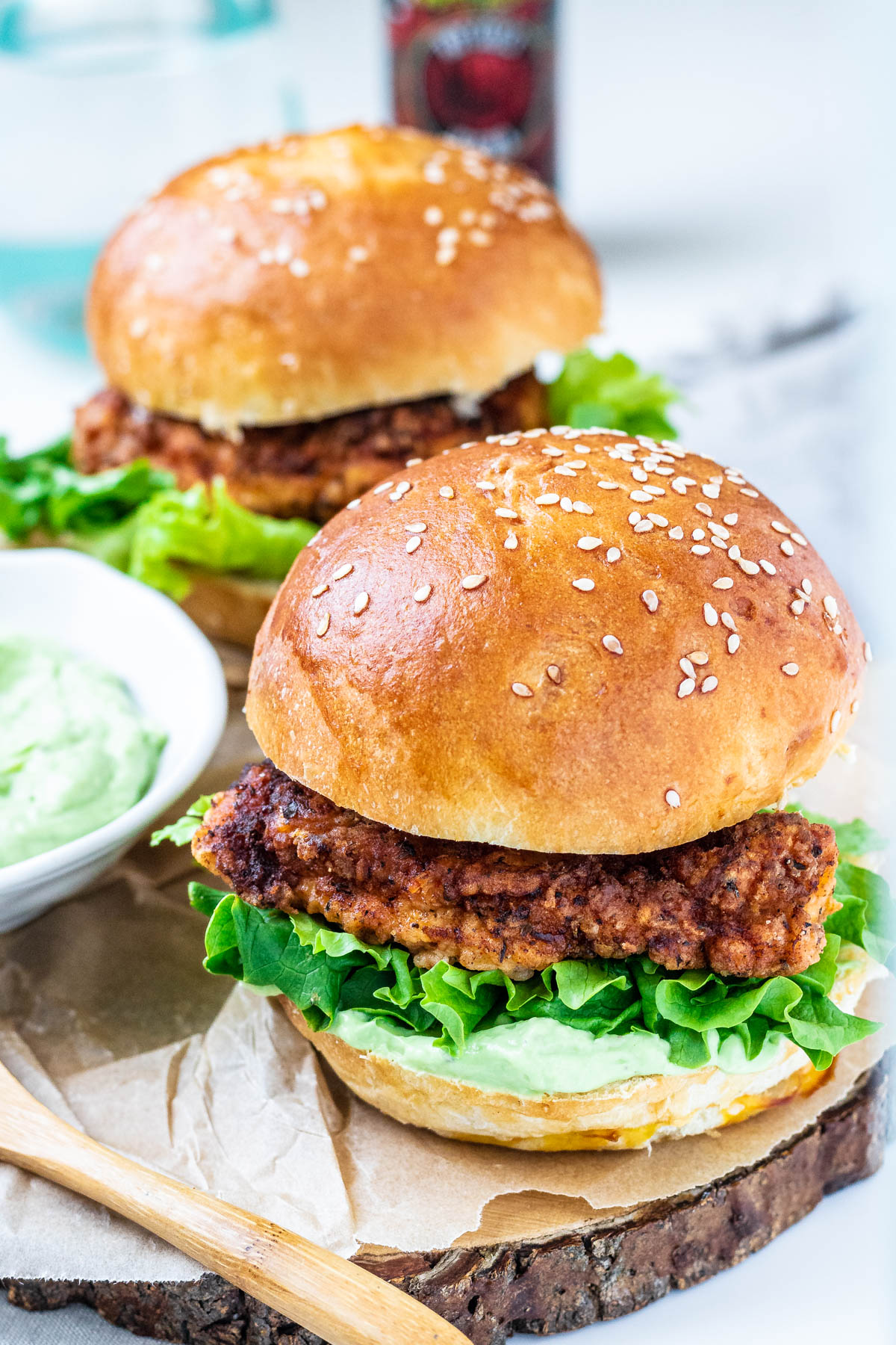 chicken burgers on a plate with a bowl of avocado sauce.