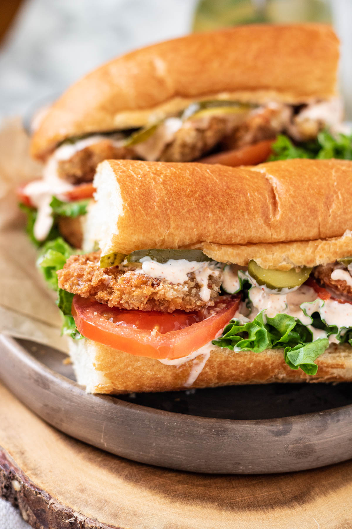 A sandwich filled with mushrooms, lettuce and tomato, on a wood platter.