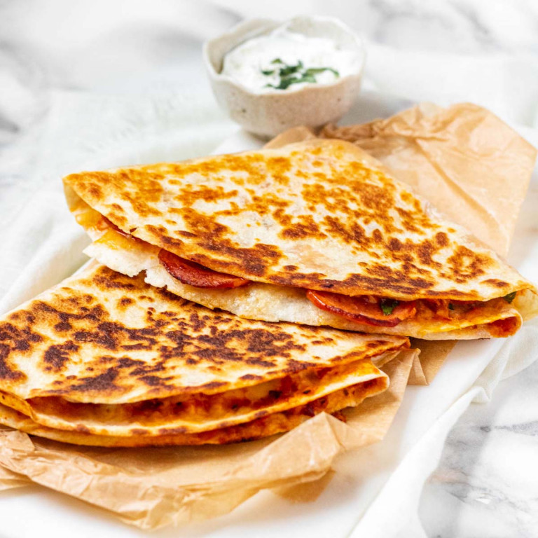 A folded pizza tortilla on a white board.