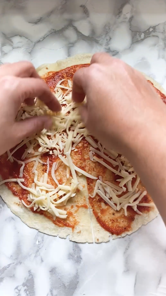 Adding cheese to a pizza quesadilla.