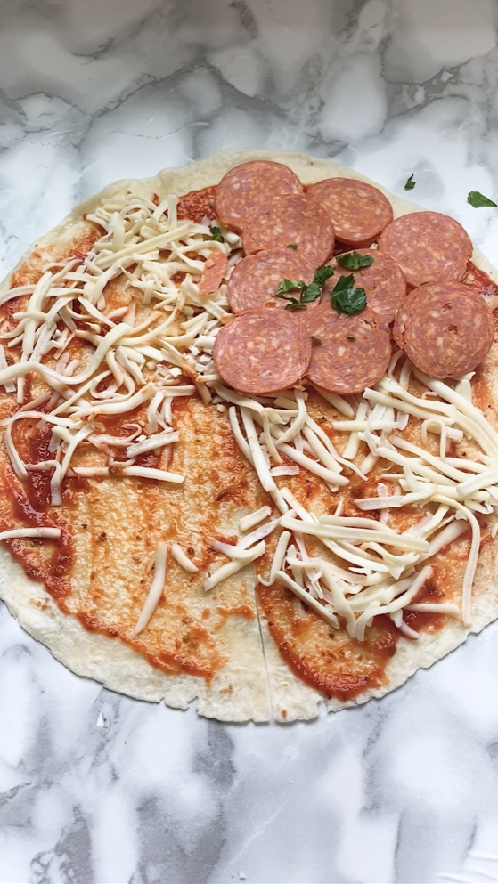 Adding cheese and pepperoni inside of a pizza quesadilla.