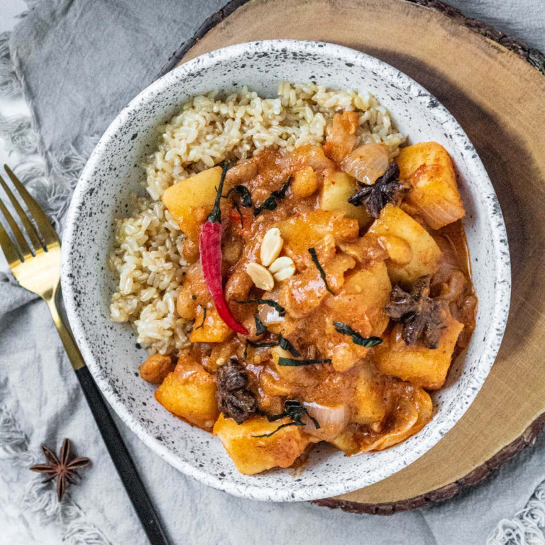 Massaman curry in a white and black speckled bowl.