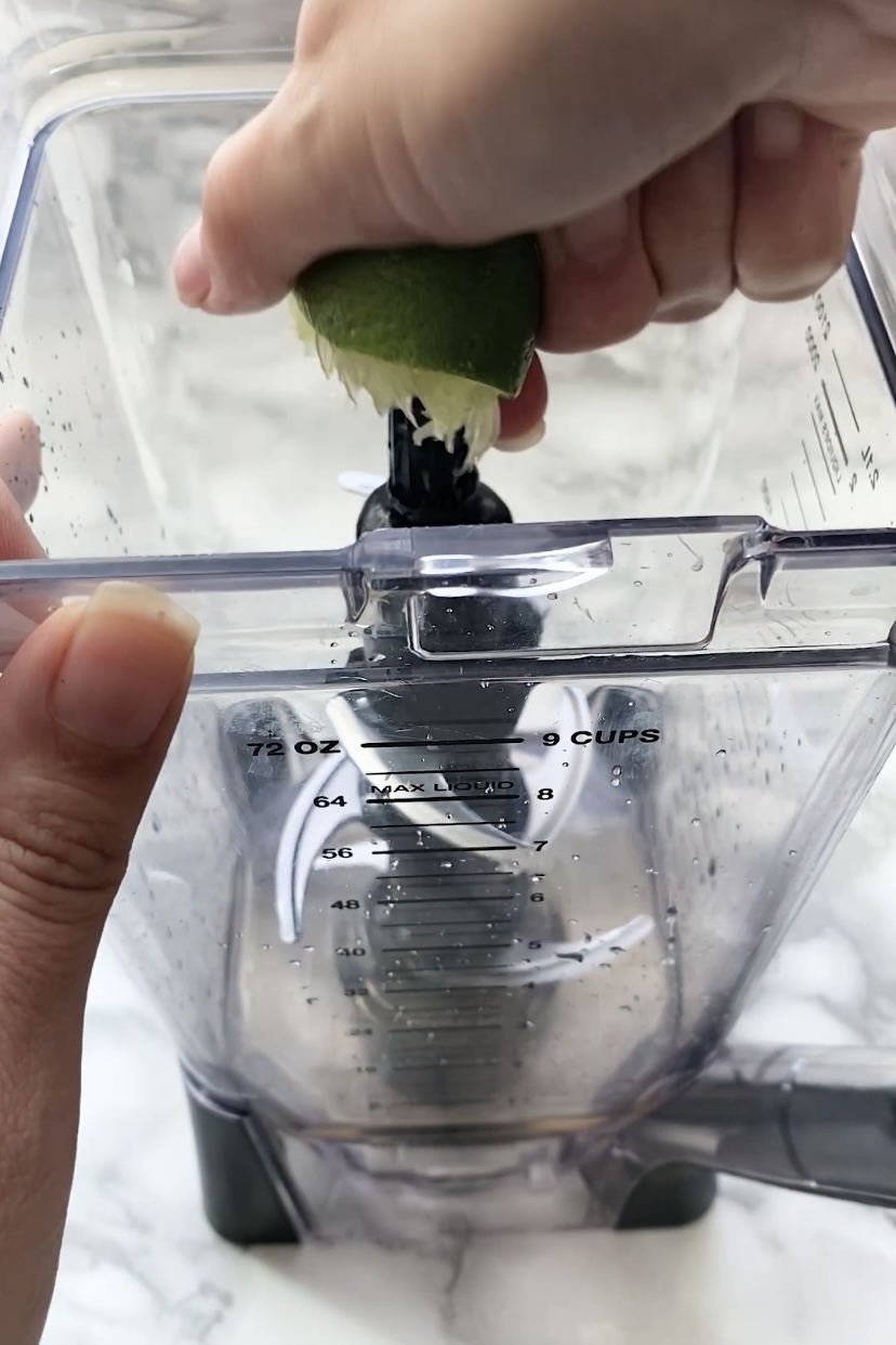 Squeezing lime juice into a blender.
