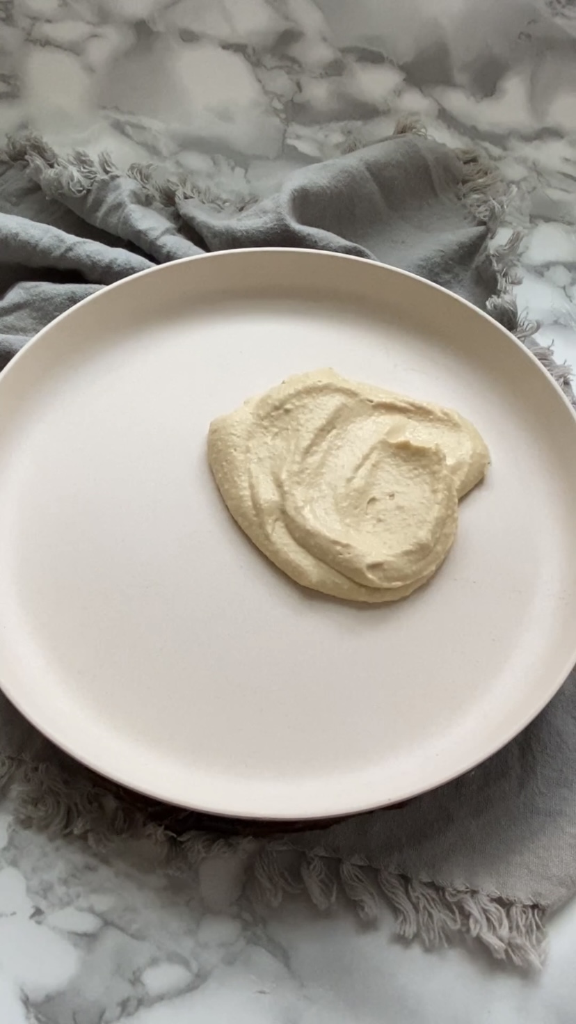 A plate with hummus spread out on it.
