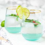 Two cocktails garnished with Thai leaves and chilies on a marble background.