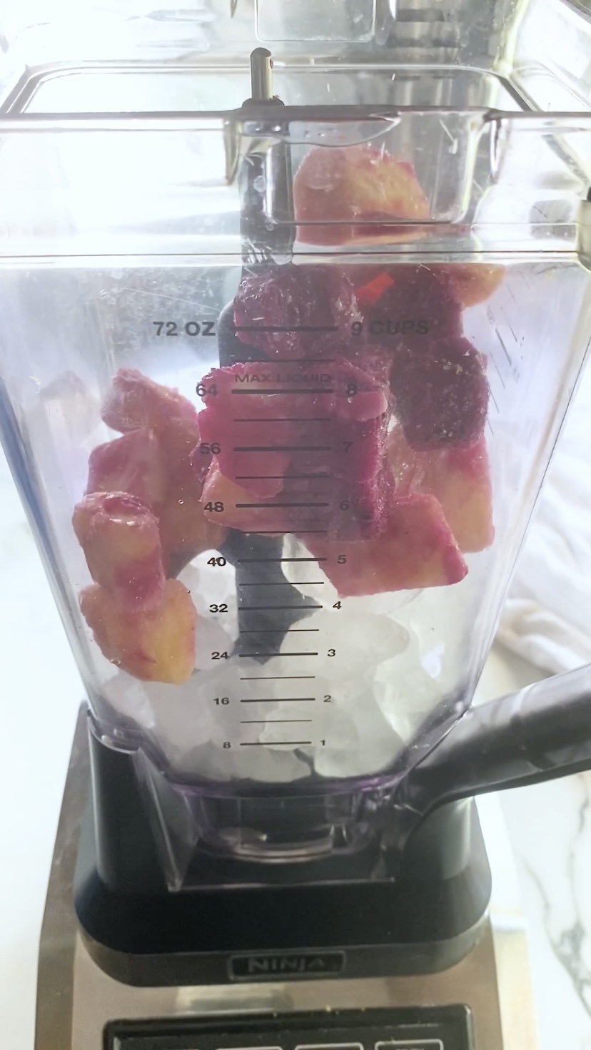 A blender with frozen fruit and ice in it.