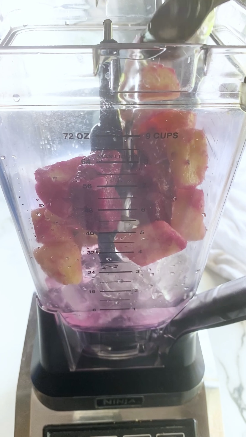 Adding liquid to a blender with frozen fruit and ice it.