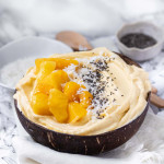 A mango smoothie bowl in a coconut bowl with mango chunks on top.