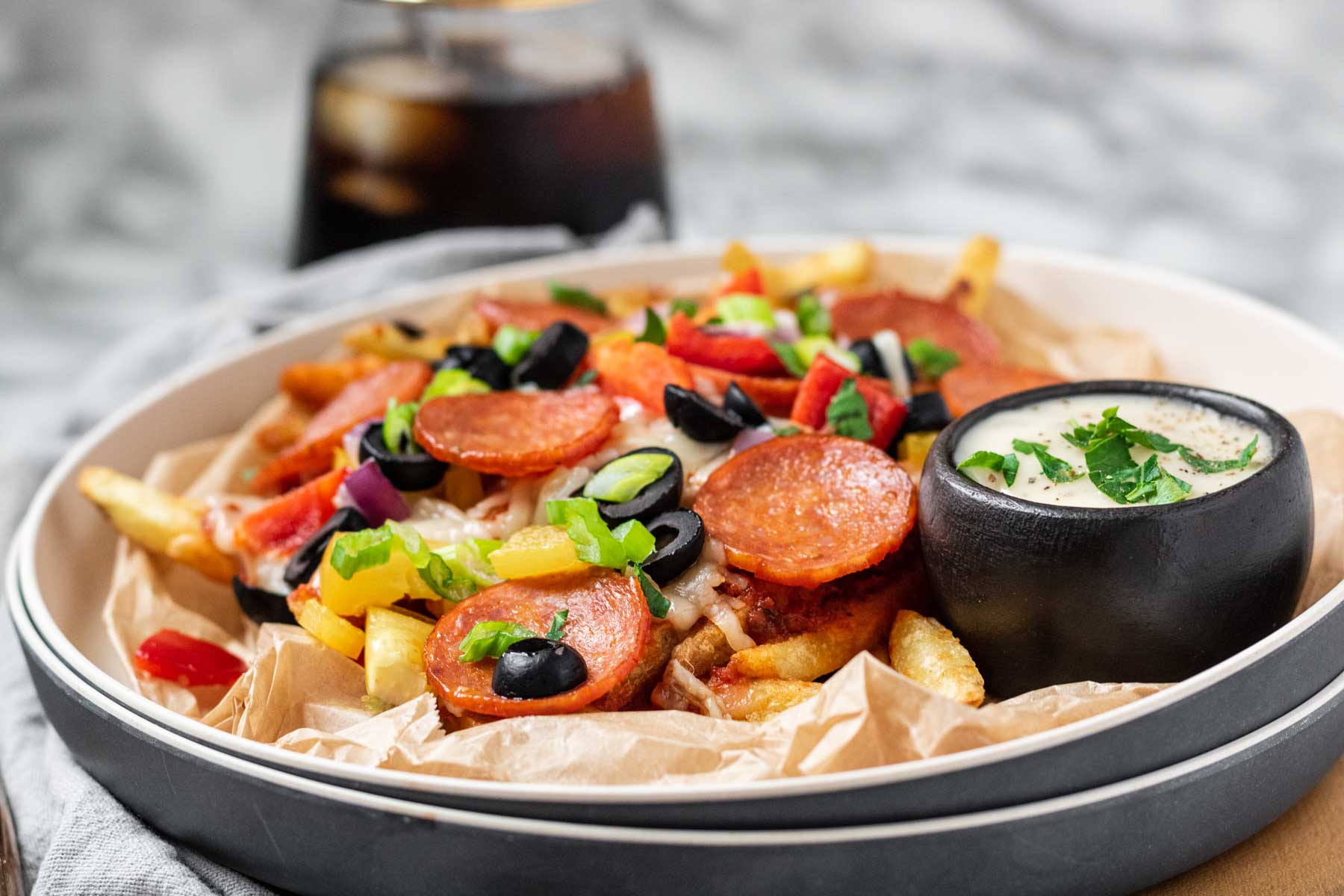 Baked fries on a plate with pizza toppings on top.