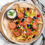 Baked fries on a plate with pizza toppings on top.