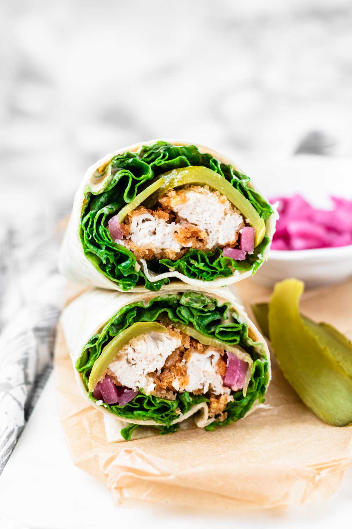 The cut ends of two stacked wraps filling with lettuce, crispy chicken, and lettuce.