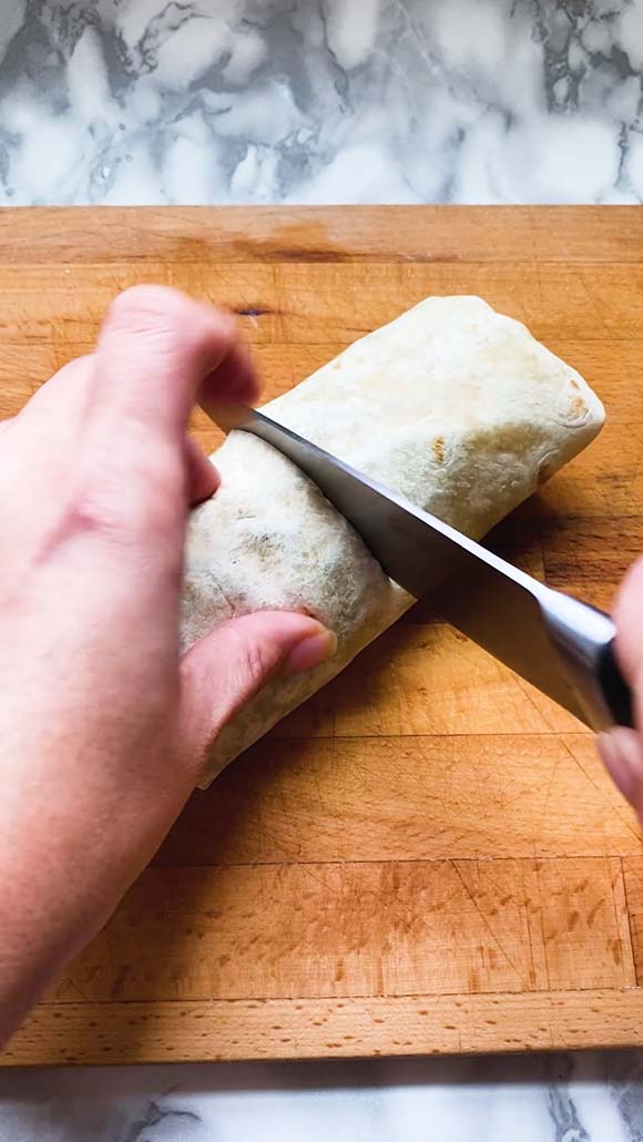Cutting a wrap in half with a knife.