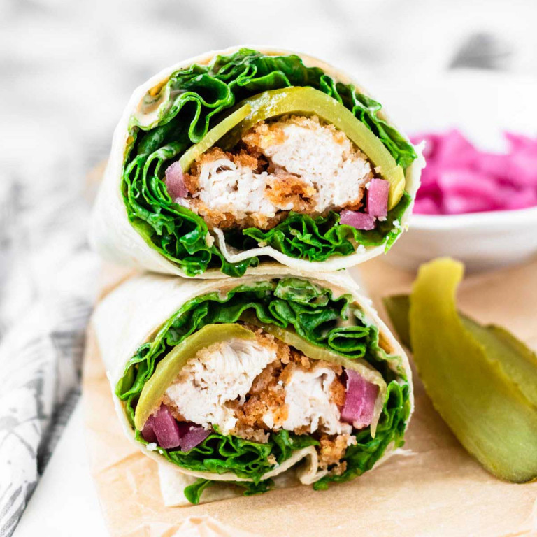 The cut ends of two stacked wraps filling with lettuce, crispy chicken, and lettuce.