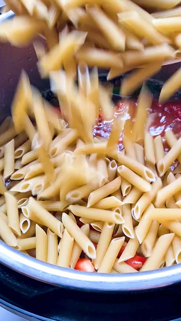 Adding pasta to other ingredients in an Instant Pot.
