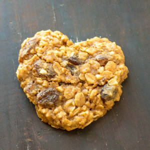 Heart shaped Oatmeal Raisin Cookies on a dark counter.